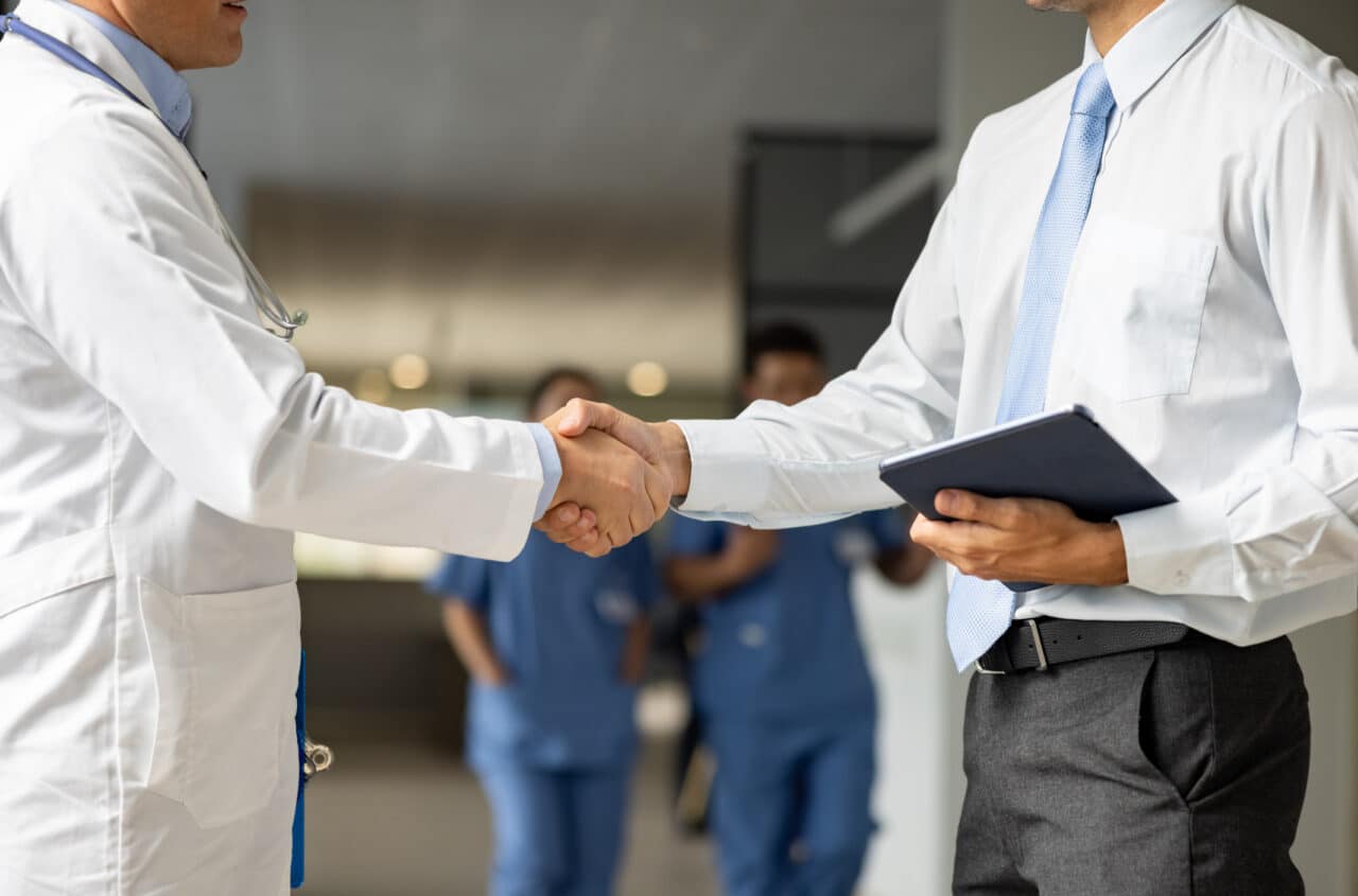 Close up on a medical insurance agent greeting a doctor with a handshake