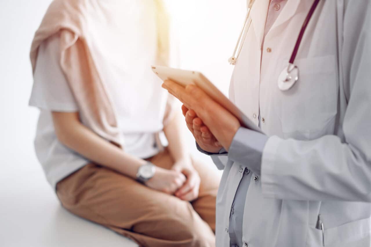 Doctor and patient discussing perfect health exam results. Friendly physician keeping tablet computer with her hands near a young woman. Medicine concept